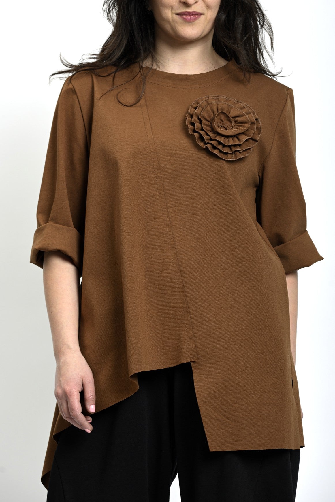 Prim-plan cu detaliul floral aplicat pe bluză asimetrică maro, cu textură fină.