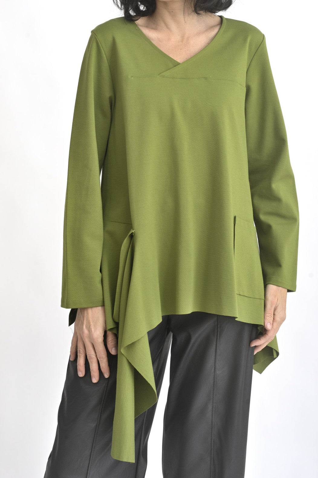 Detaliu croială asimetrică al unei bluze verzi cu mânecă lungă și bandă decorativă aplicată lateral