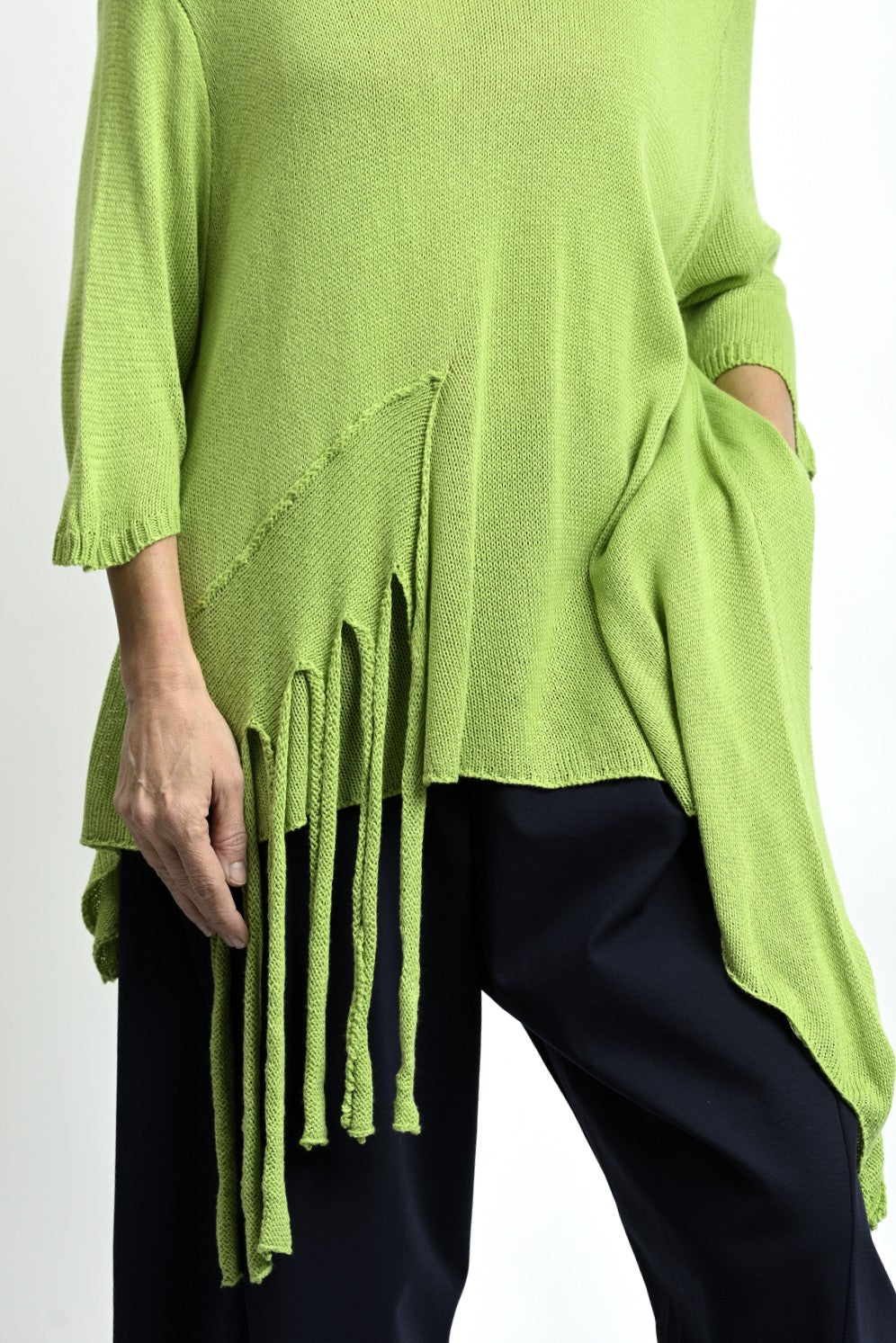 Detaliu franjuri pe bluză verde cu colț, accent boem care adaugă mișcare și personalitate.