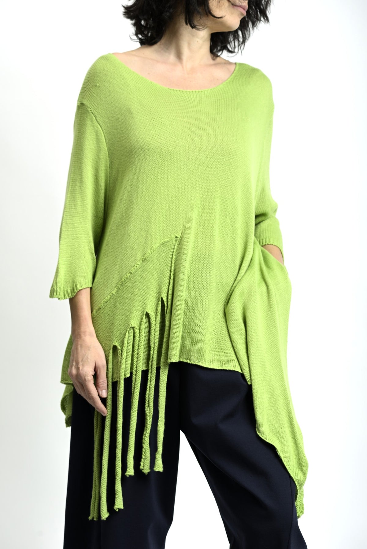 Bluză verde cu franjuri, vedere completă, lungime asimetrică și textură fluidă, purtată cu pantaloni largi.