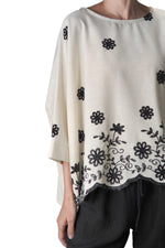 Detaliu cu broderia florală elegantă aplicată pe partea inferioară a bluzei.