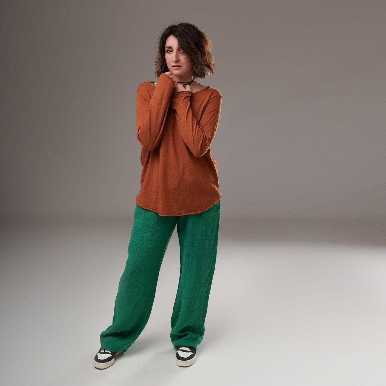 Bluză cărămizie cu mâneci lungi, purtată cu pantaloni verzi, look casual