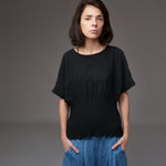Model purtând bluză neagră cu mânecă scurtă tip fluture, combinată cu pantaloni din denim lejer.