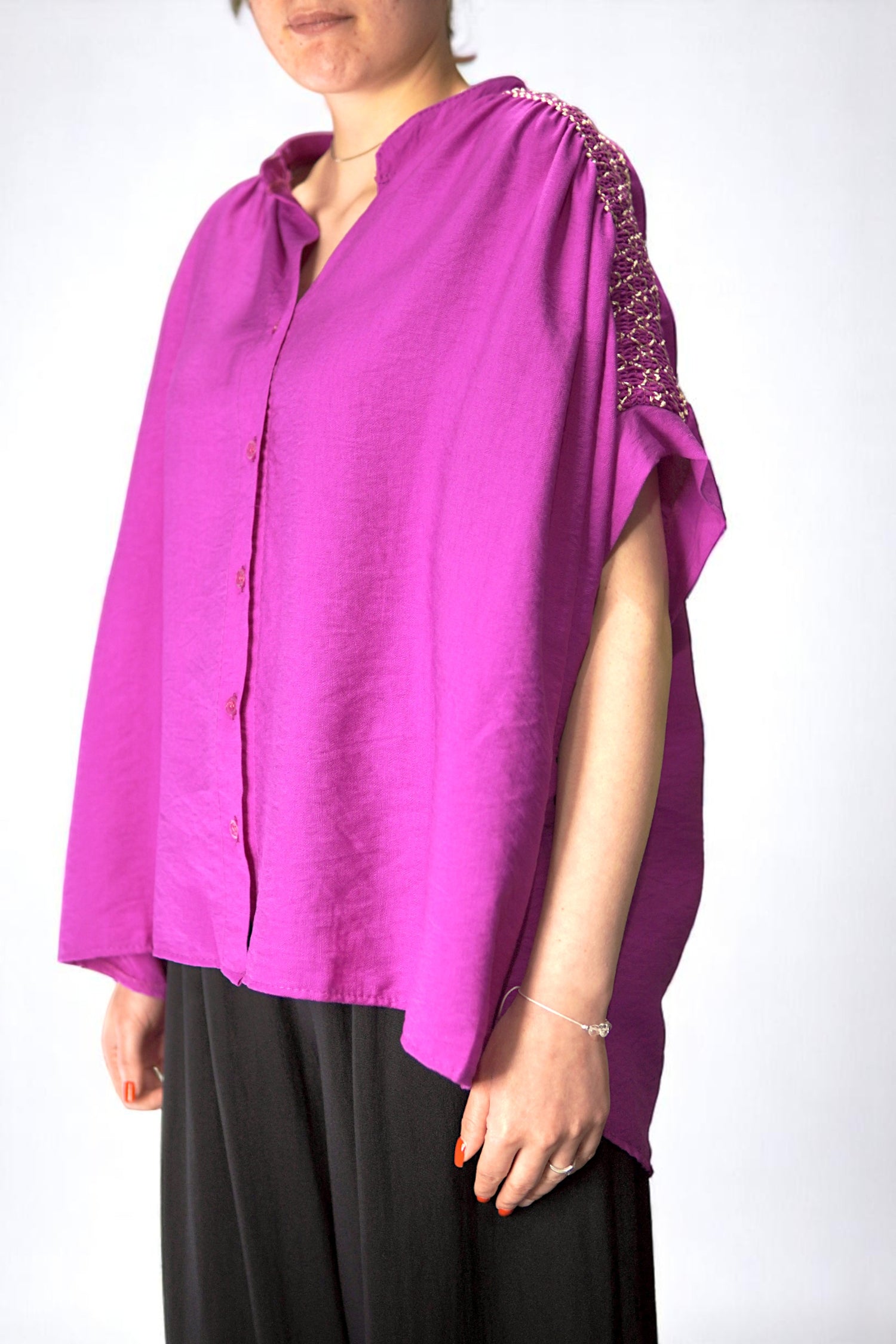 Bluza lejeră fucsia cu broderie aurie pe umeri, purtată cu pantaloni negri