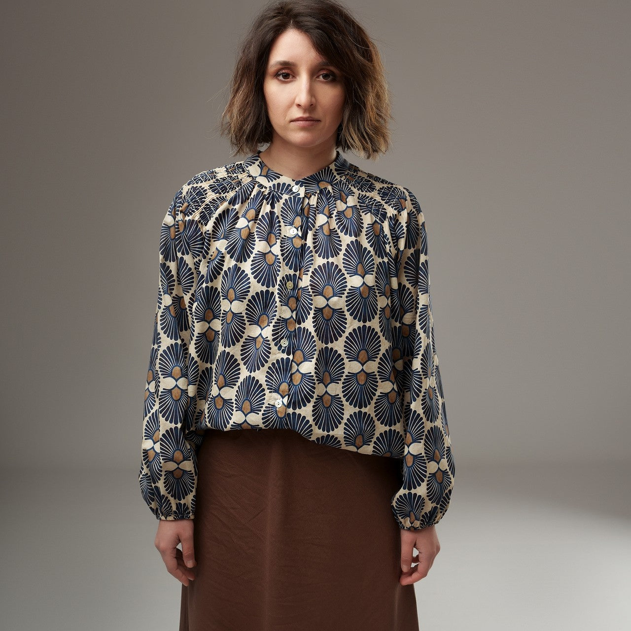 Bluză florală asortată cu fustă midi cognac, evidențiind croiala largă și imprimeul geometric floral.