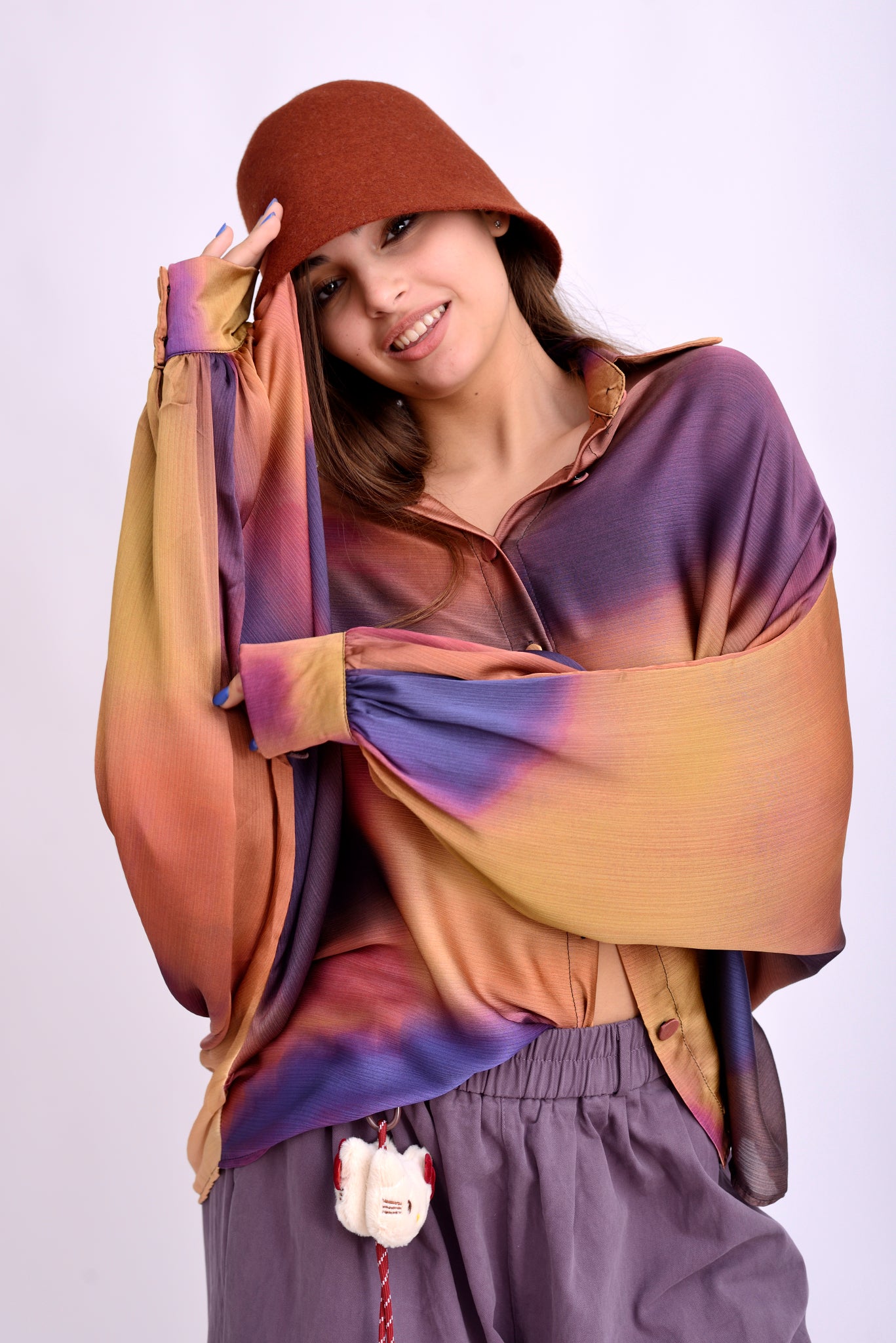 Model purtând bluză kaftan cu imprimeu artistic violet-oranj, material subțire și lejer.