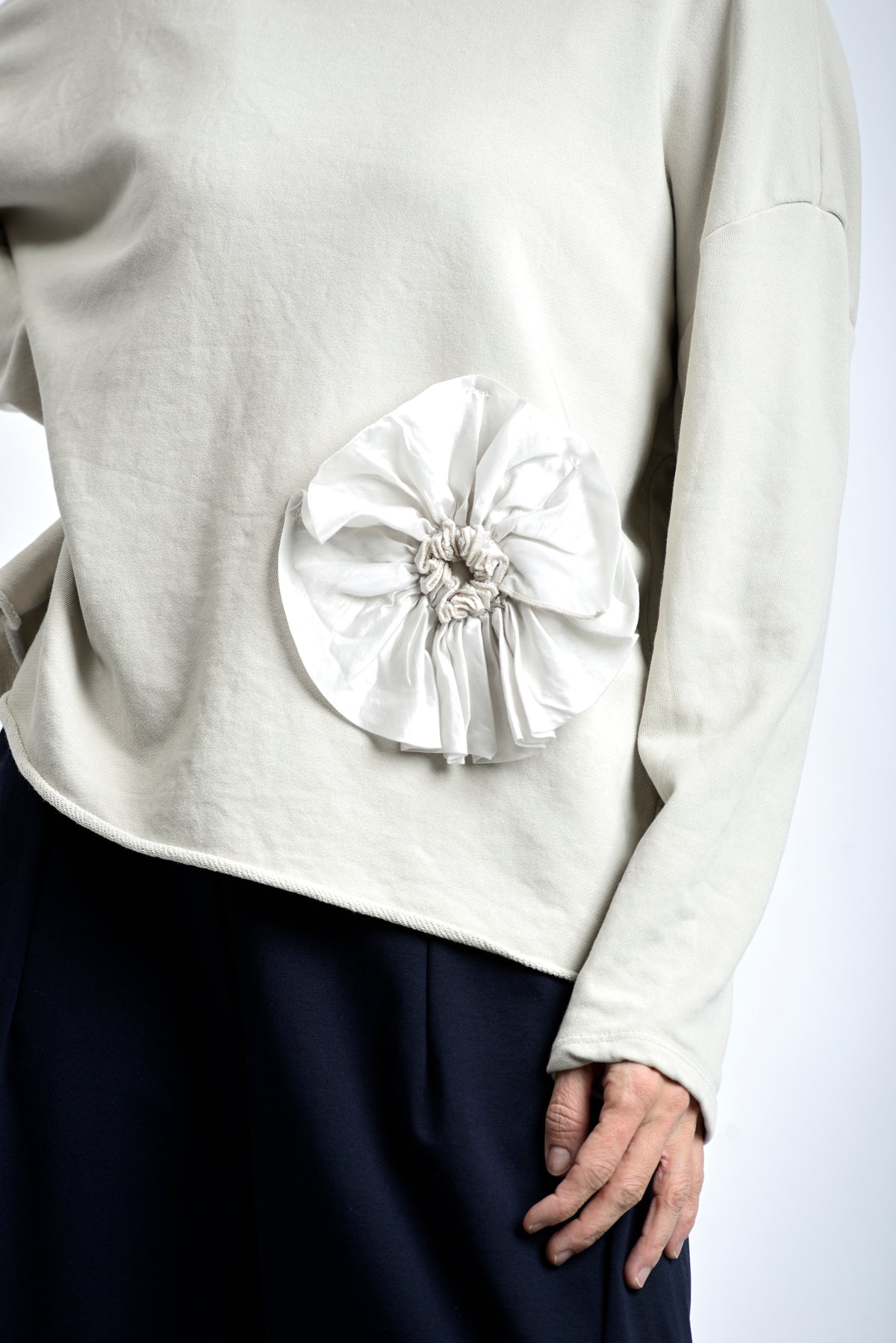 Detaliu de aplicație floare textilă la baza bluzei din jerse de bumbac.