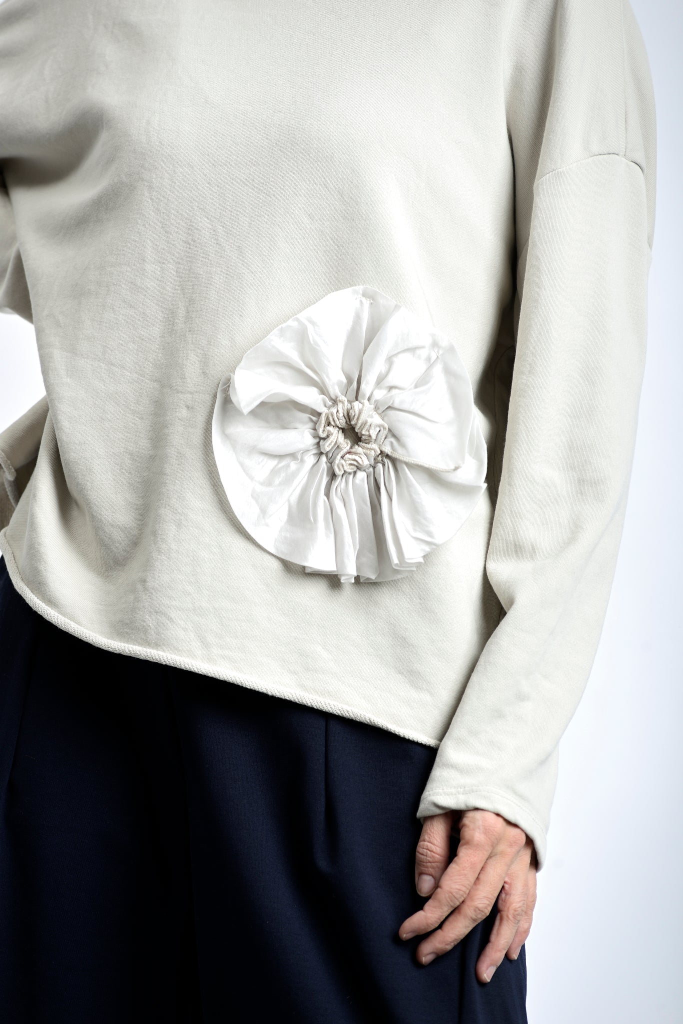 Detaliu de aplicație floare textilă la baza bluzei din jerse de bumbac.