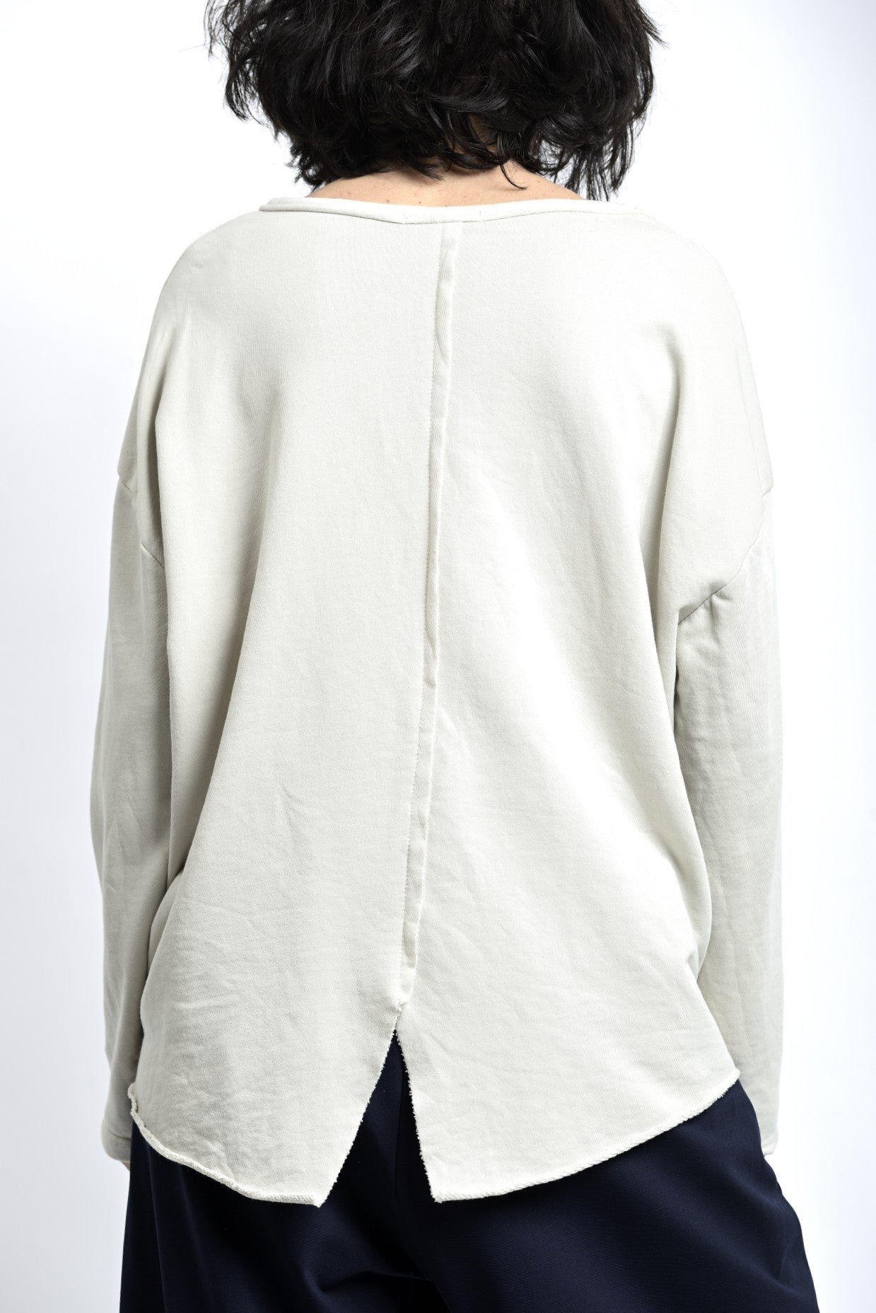 Spatele bluzei largi cu despicătură tip coadă de rândunică și lungime prelungită.