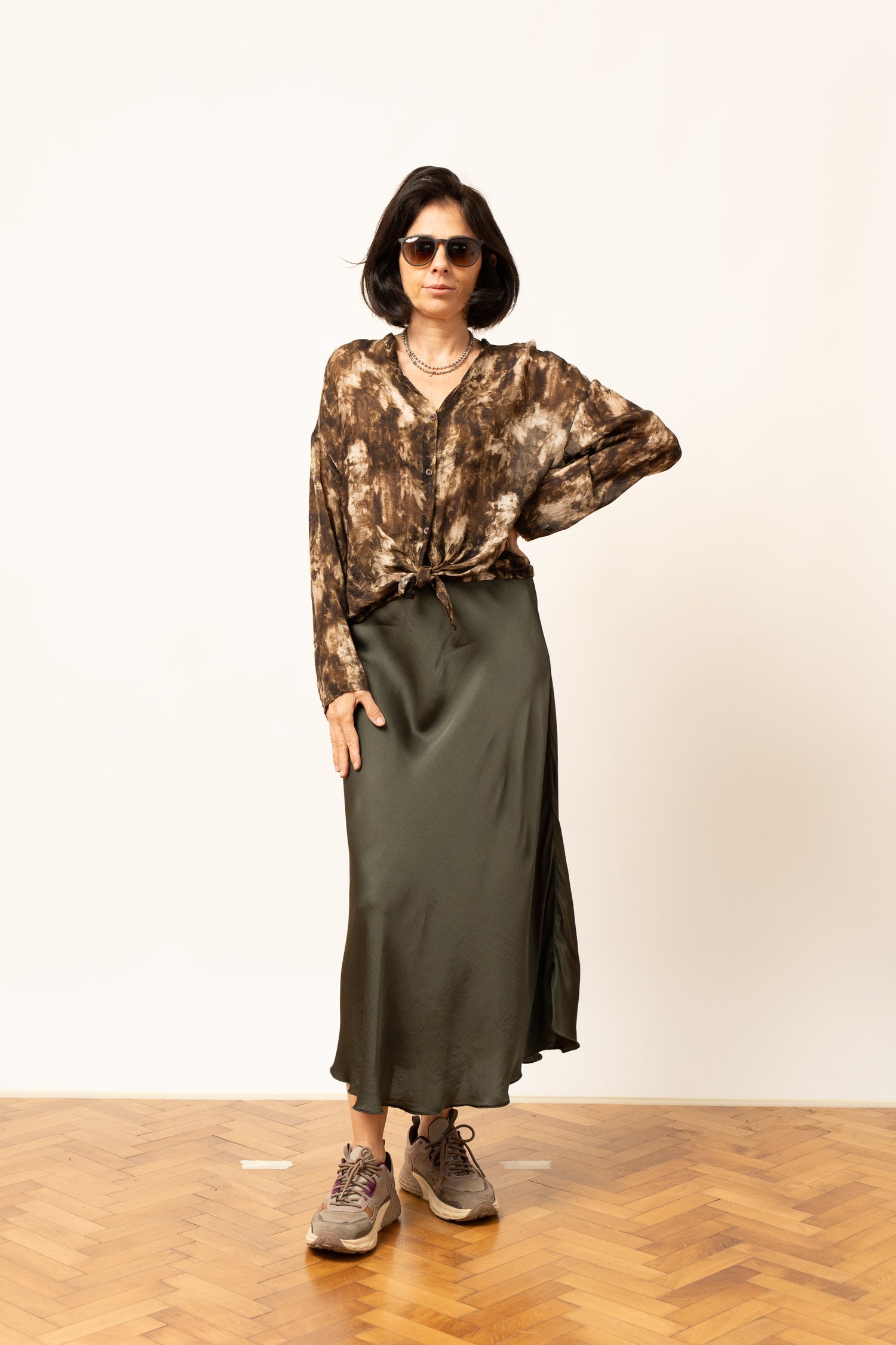 Bluza cu imprimeu abstract maroniu, purtată cu fustă lungă verde, vedere frontală.