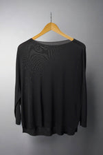  Bluza neagră largă, semi-transparentă, cu croială lejeră și tiv ușor asimetric.