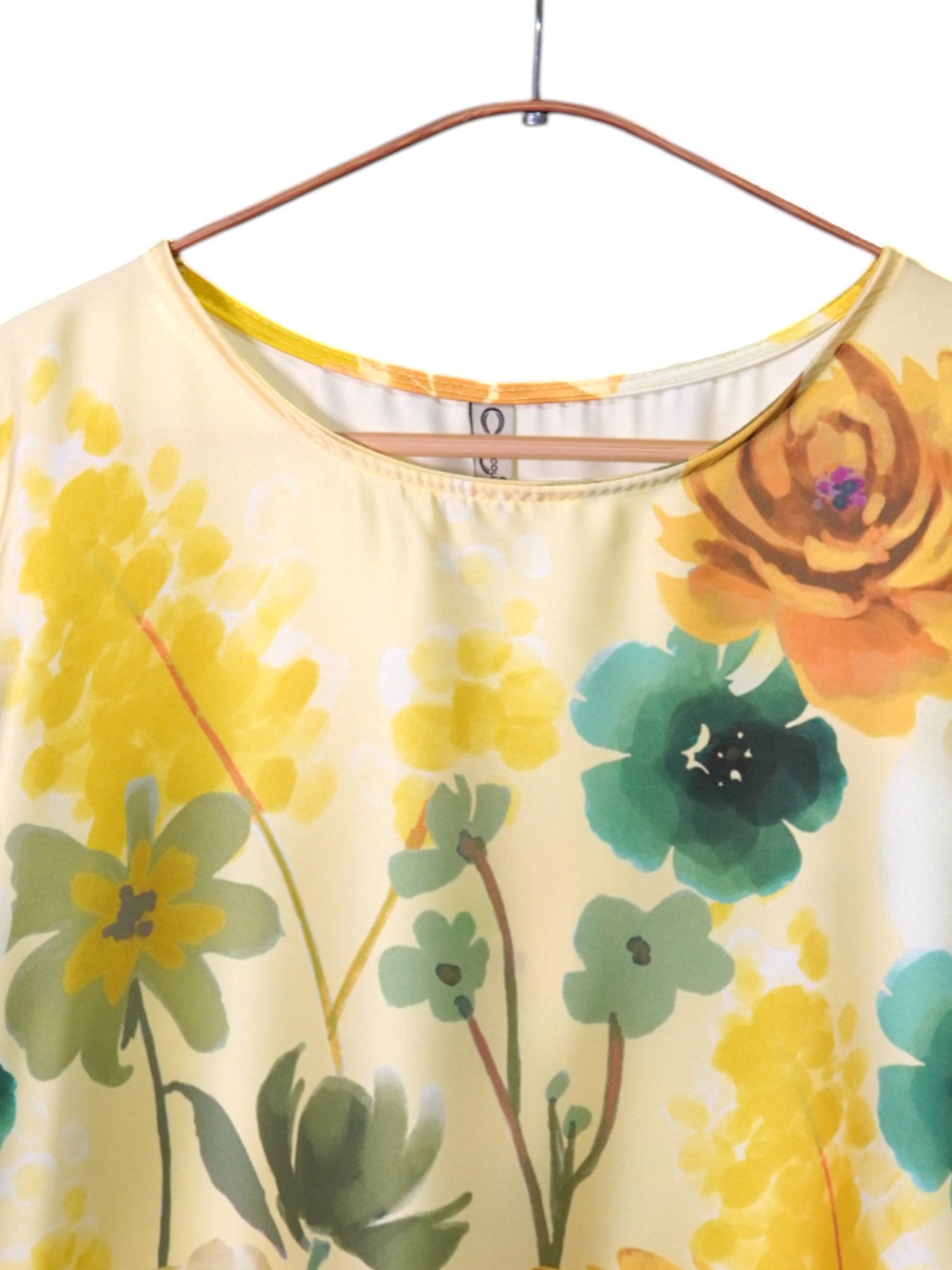Detaliu decolteu rotund al unei bluze satinate galbene cu imprimeu floral