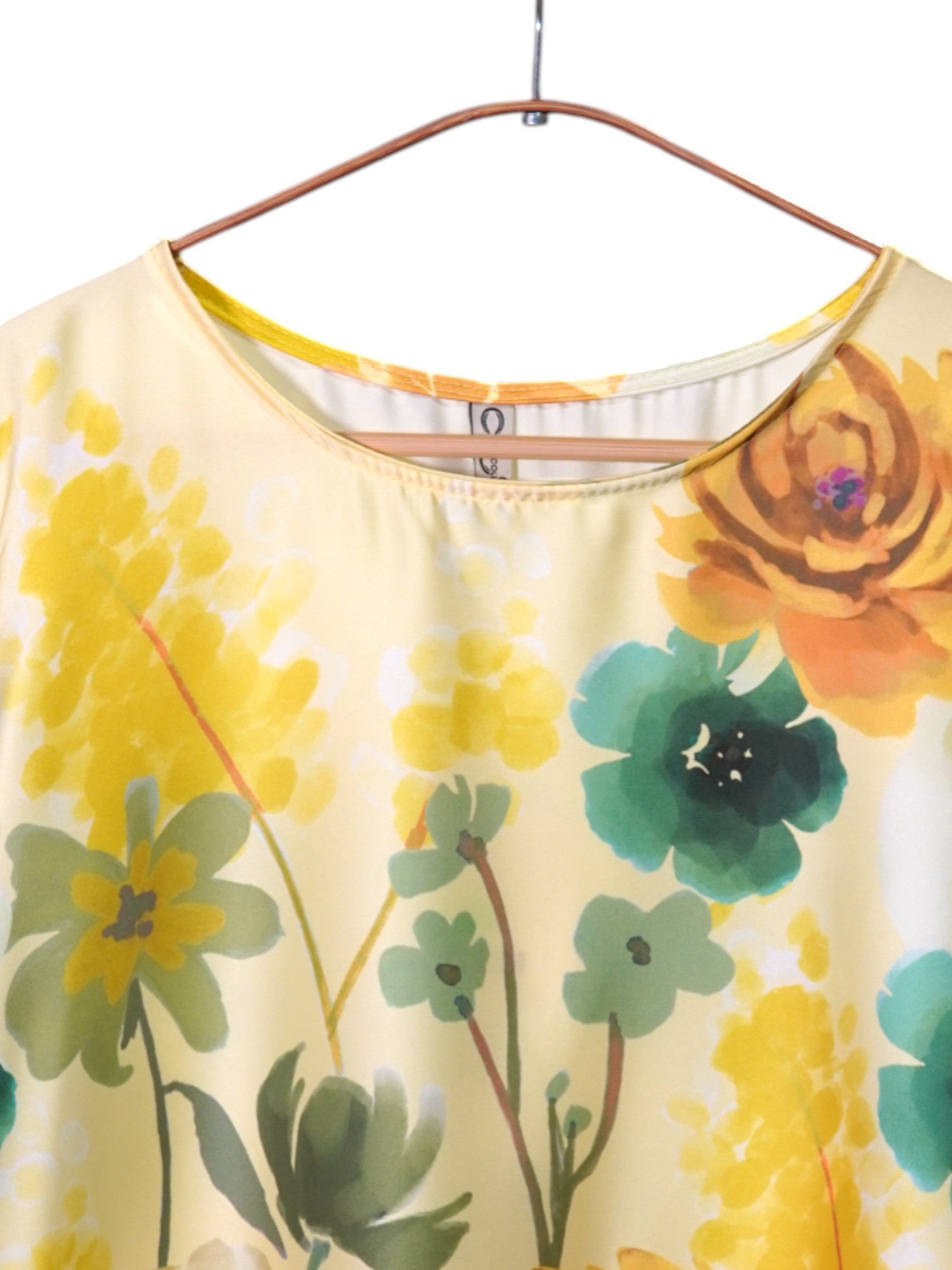 Detaliu decolteu rotund al unei bluze satinate galbene cu imprimeu floral
