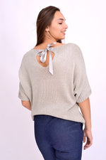 Detaliu fundă la spate pe bluză din tricot auriu cu sclipici, design feminin și rafinat.