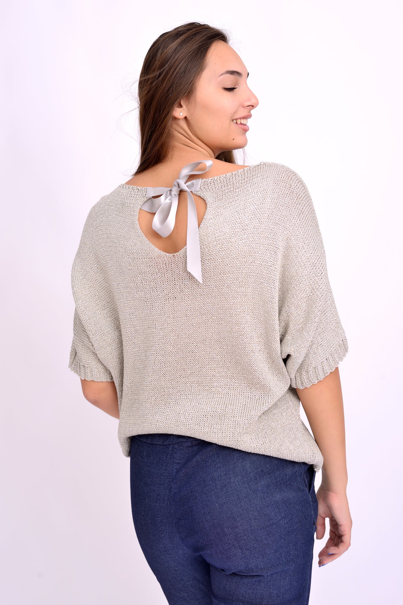 Detaliu fundă la spate pe bluză din tricot auriu cu sclipici, design feminin și rafinat.