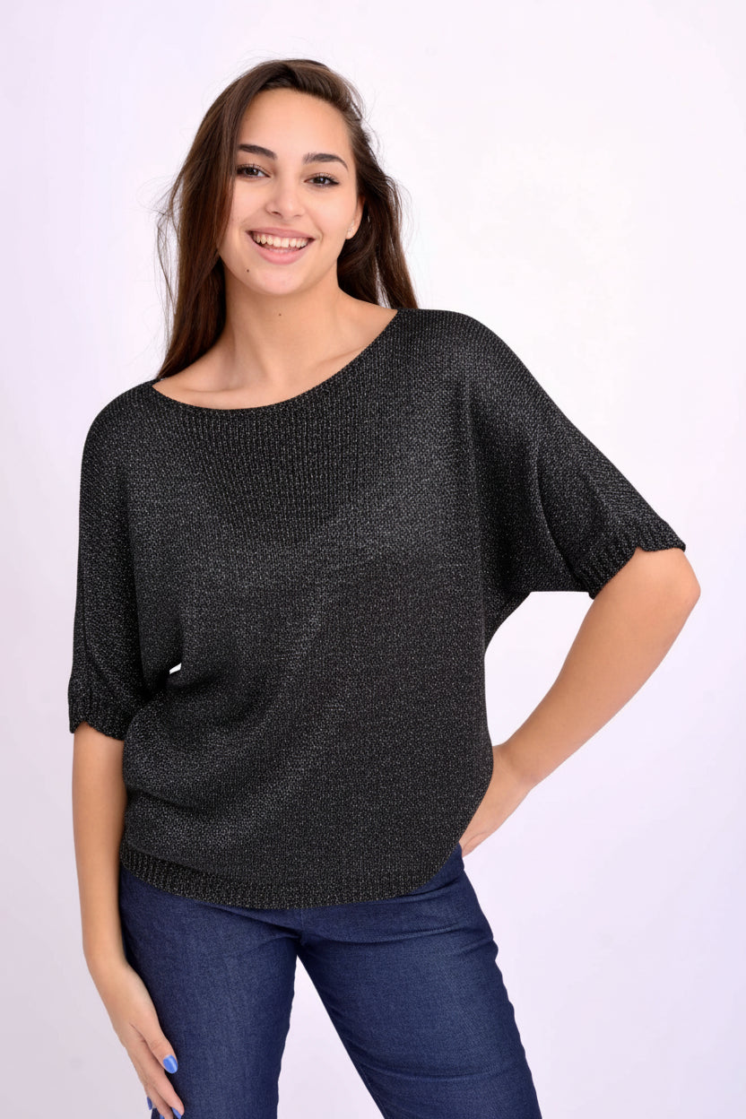 Bluză negru-argintie din tricot subțire cu sclipici și fundă la spate, purtată pe model.