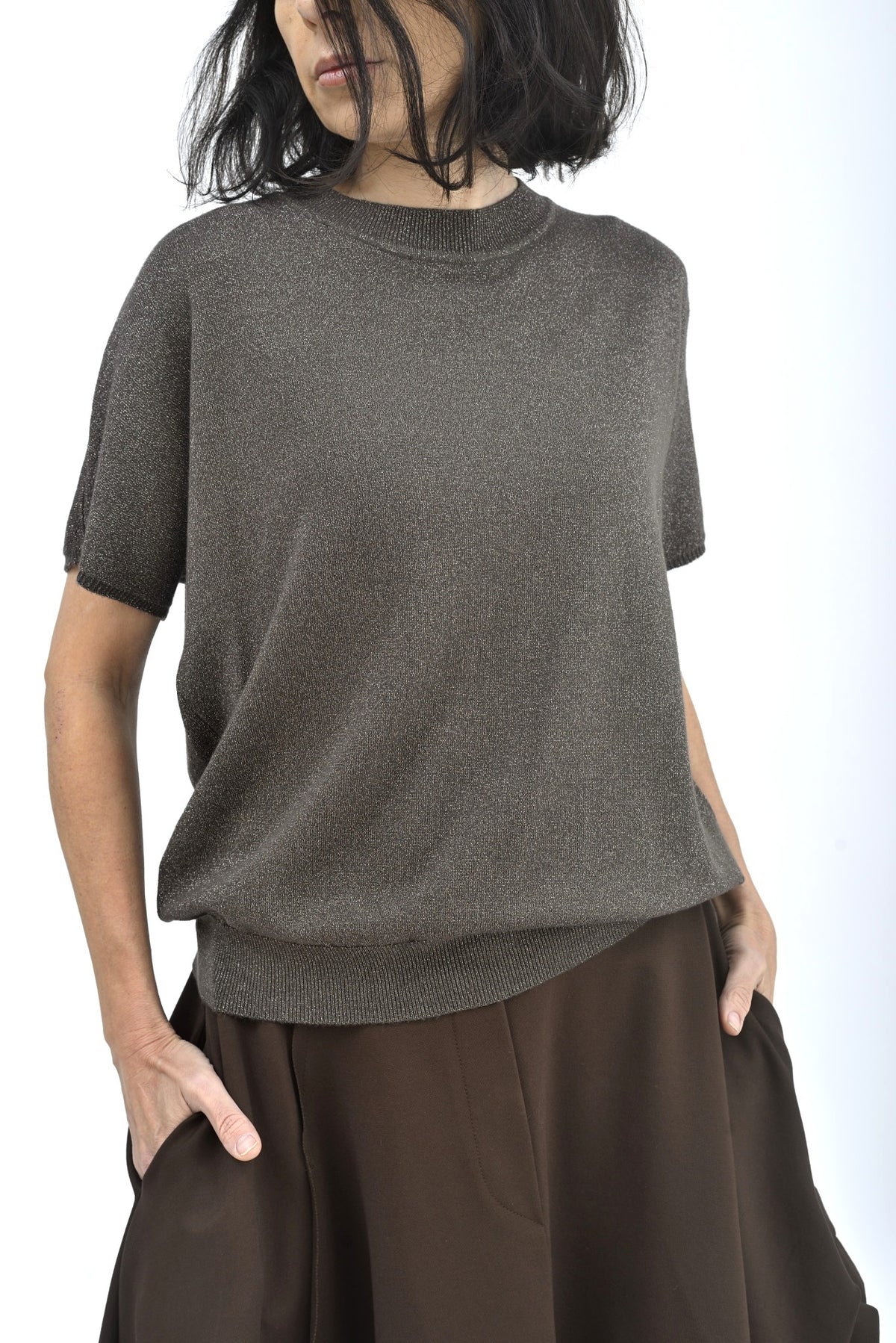 Detaliu guler rotund al unei bluze cu sclipici discret și textură fină