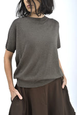 Detaliu guler rotund al unei bluze cu sclipici discret și textură fină