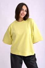 Top galben cu mânecă trei sferturi, umeri căzuți și textură fină, vedere laterală pe model.