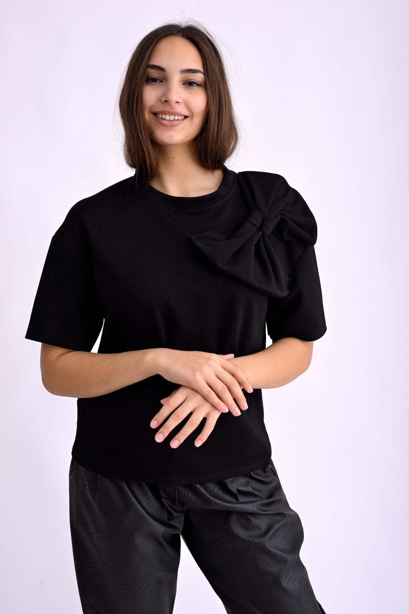 Profil al topului negru din material elastic, croială dreaptă cu fundă textilă decorativă.