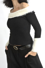 Vedere din laterala a bluzei negre din tricot, cu croială mulată și decolteu larg pe umeri.