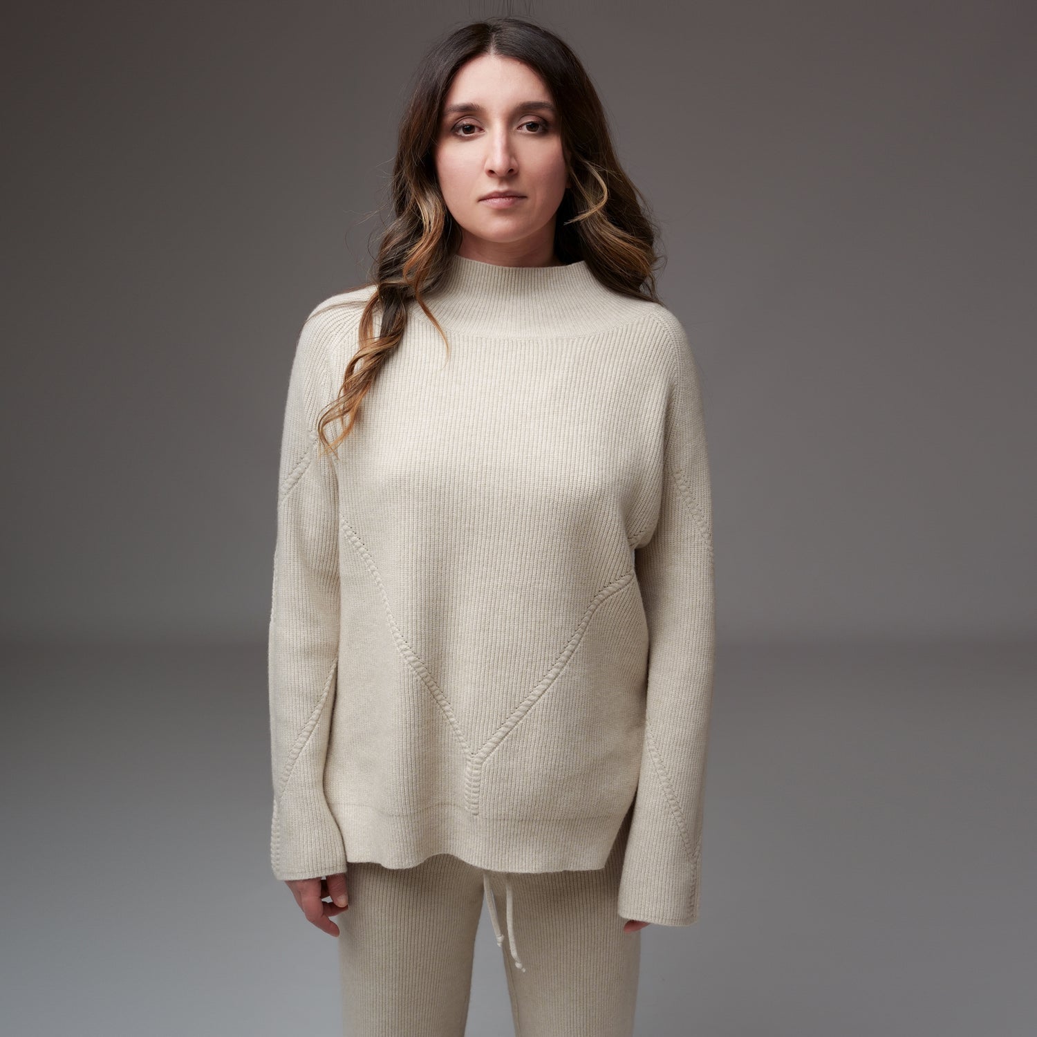 Bluză crem din tricot raiat cu model ajurat și guler turtleneck, văzută din față