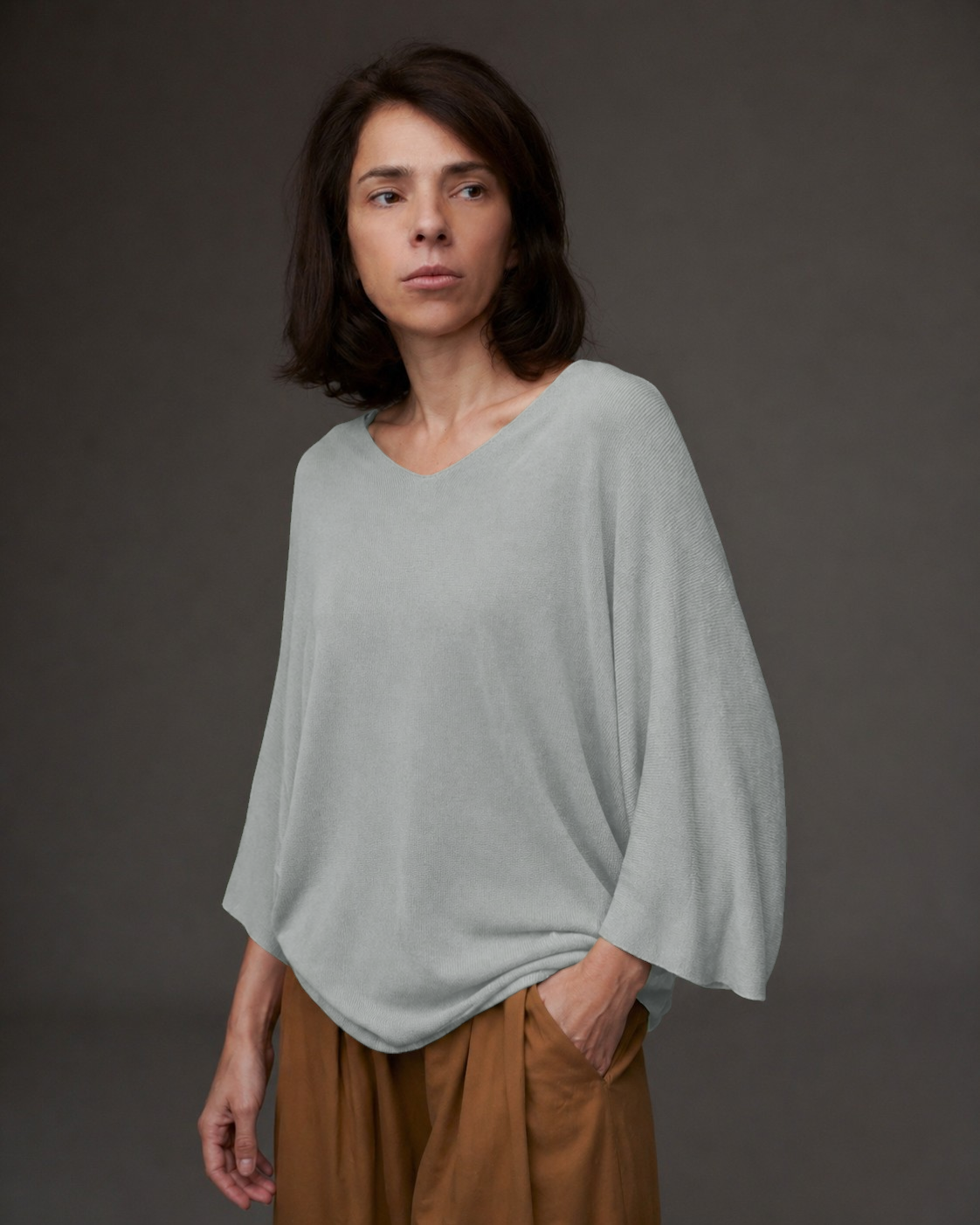 Femeie purtând bluza tricot cu decolteu în V, mâneci trei sferturi și croială lejeră.