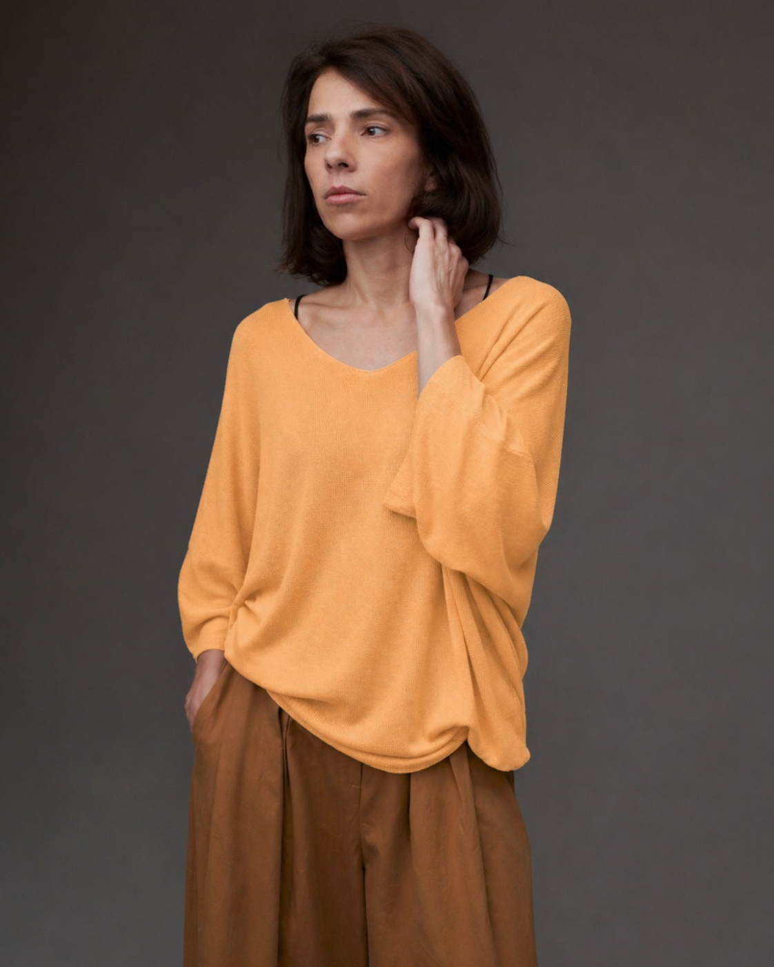 Femeie purtând bluza tricot cu decolteu în V, mâneci trei sferturi și croială lejeră.