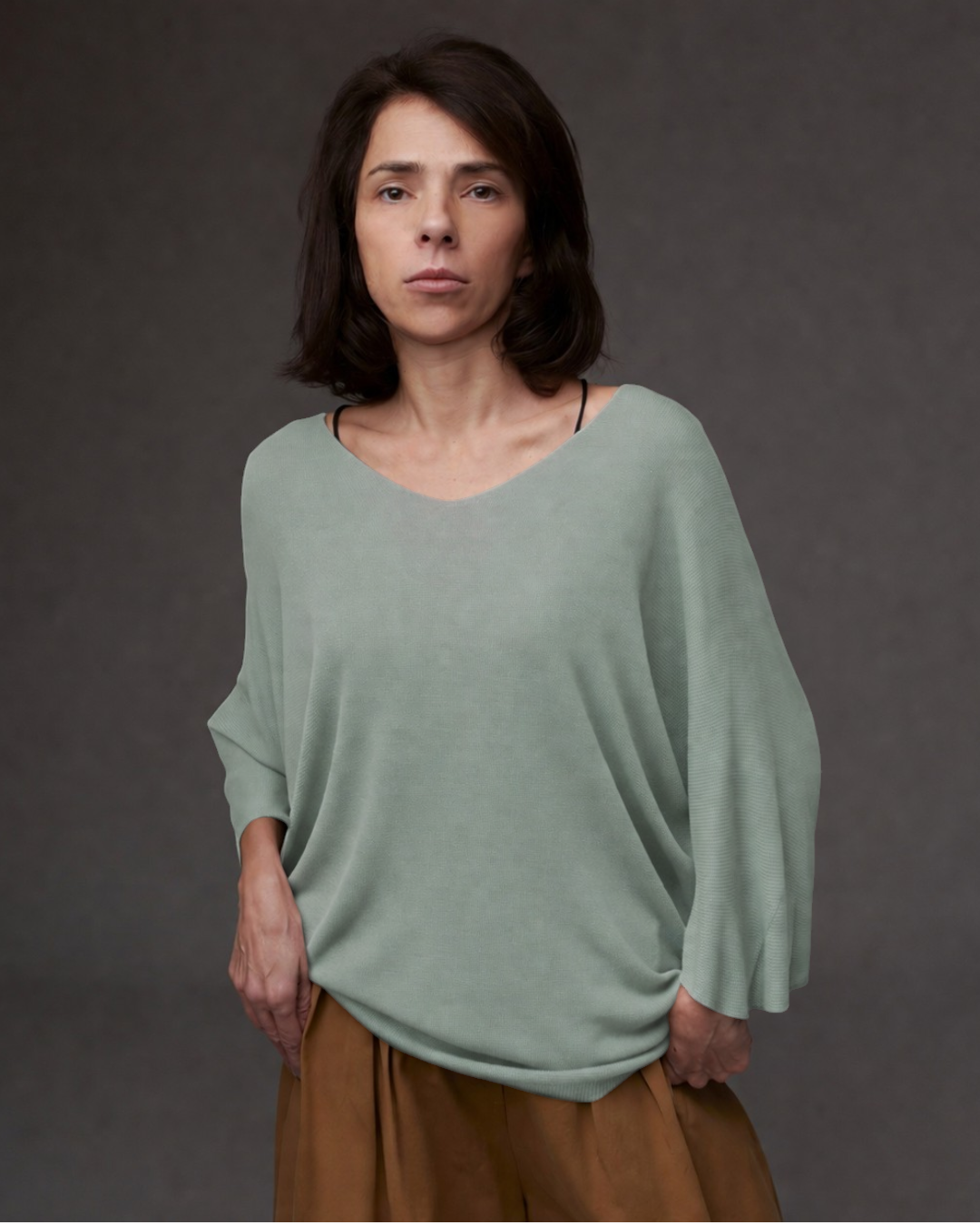 Femeie purtând bluza tricot cu decolteu în V, mâneci trei sferturi și croială lejeră.