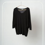 Bluza din tricot negru, ușor transparentă, cu croială amplă și decolteu adânc în V.
