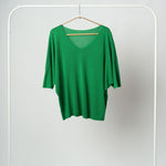 Bluza tricotată verde vibrant, cu textură fină și mâneci lejere trei sferturi, pe fundal alb.