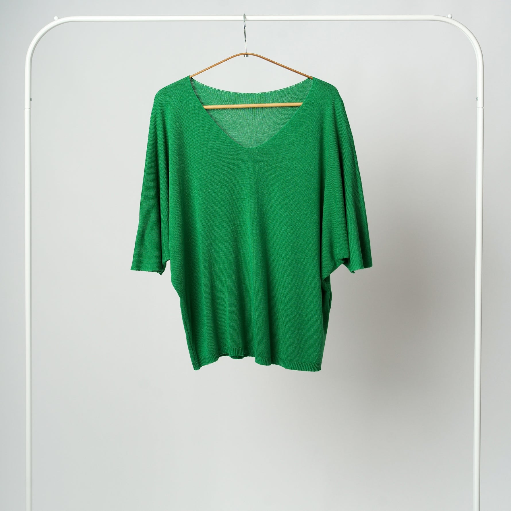 Bluza tricotată verde vibrant, cu textură fină și mâneci lejere trei sferturi, pe fundal alb.
