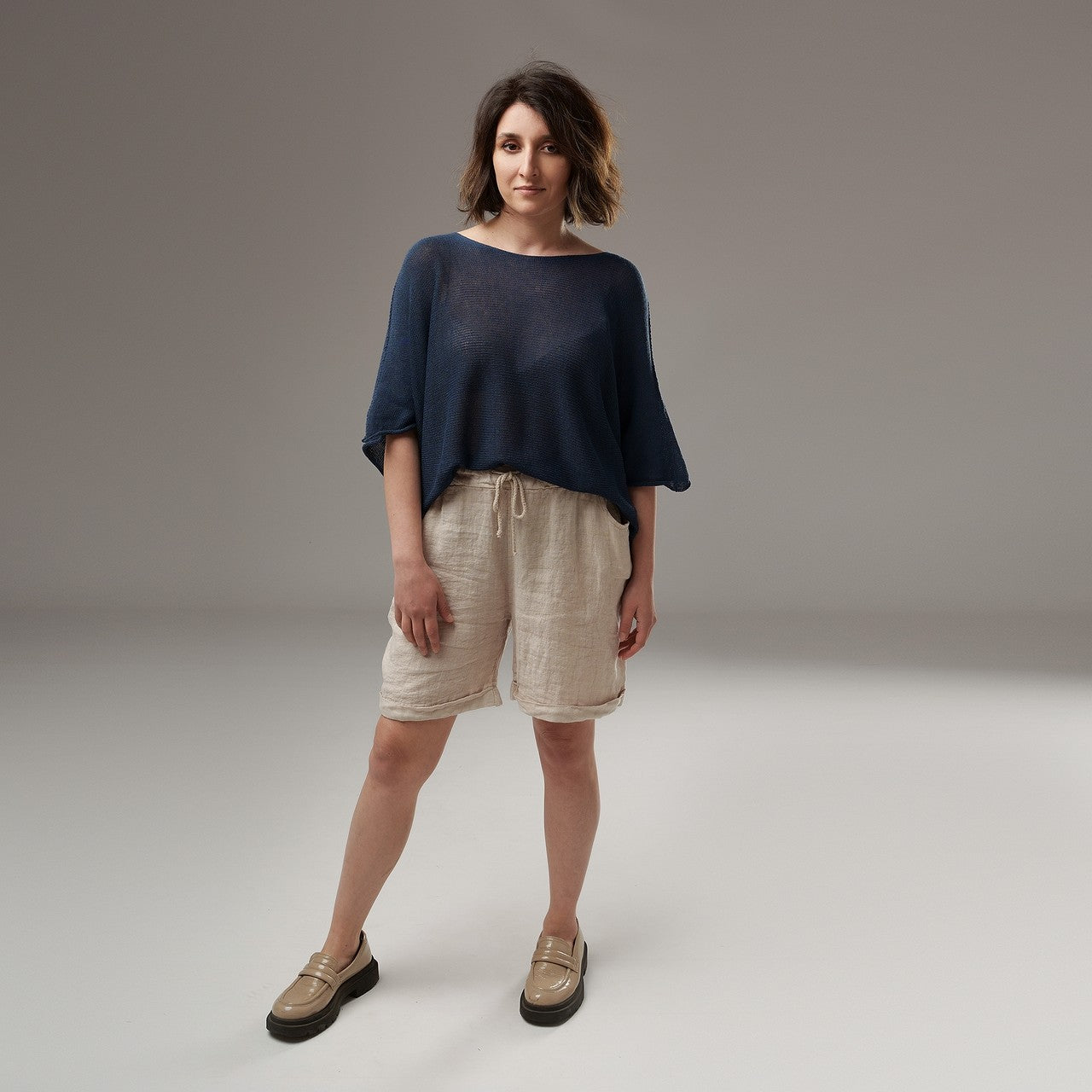  Bluză vaporoasă din tricot bleumarin, cu croială largă și mâneci scurte, asortată cu pantaloni scurți din in.