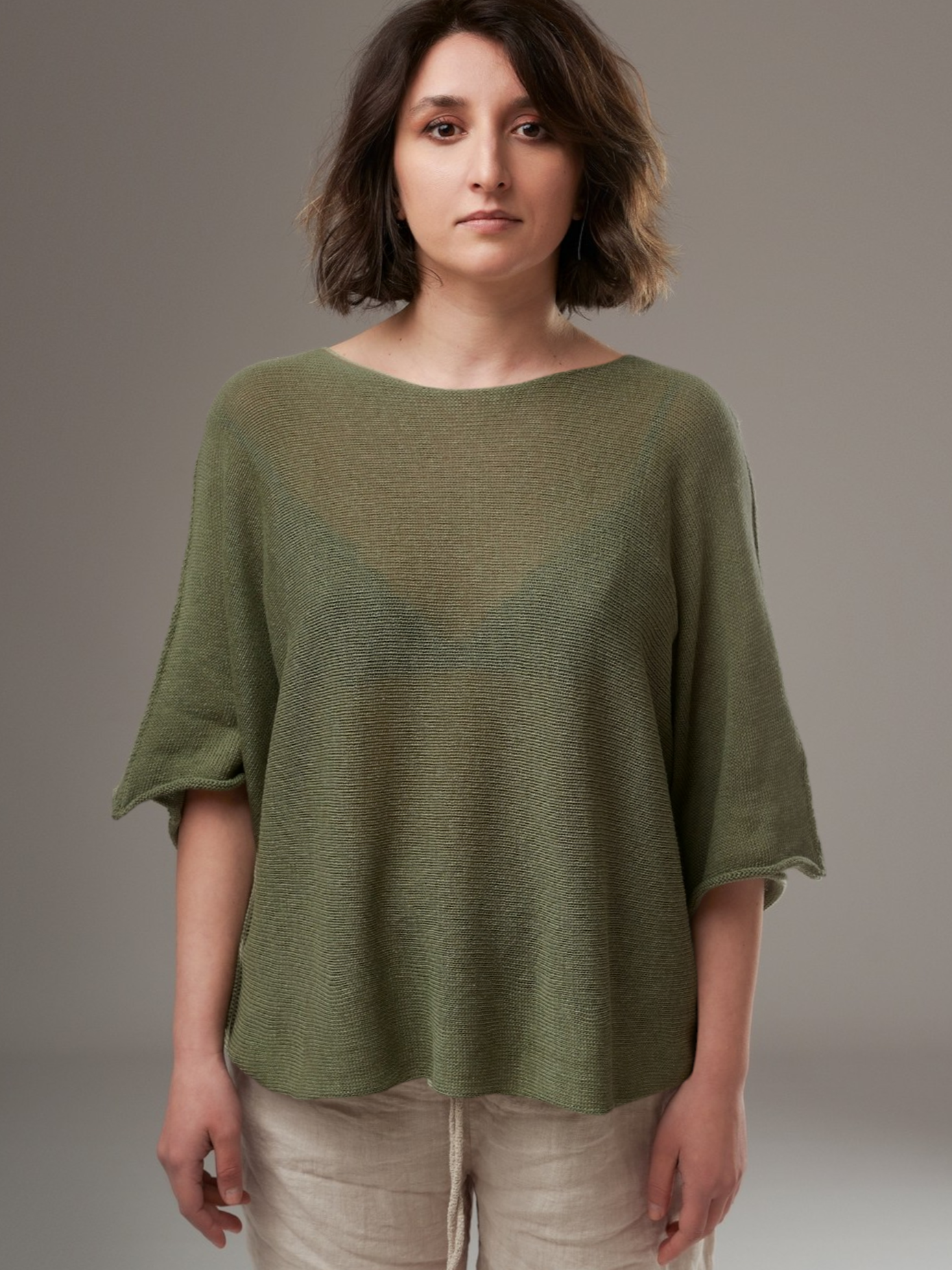 Bluză lejeră din tricot fin, în nuanță kaki, purtată cu pantaloni din in bej.