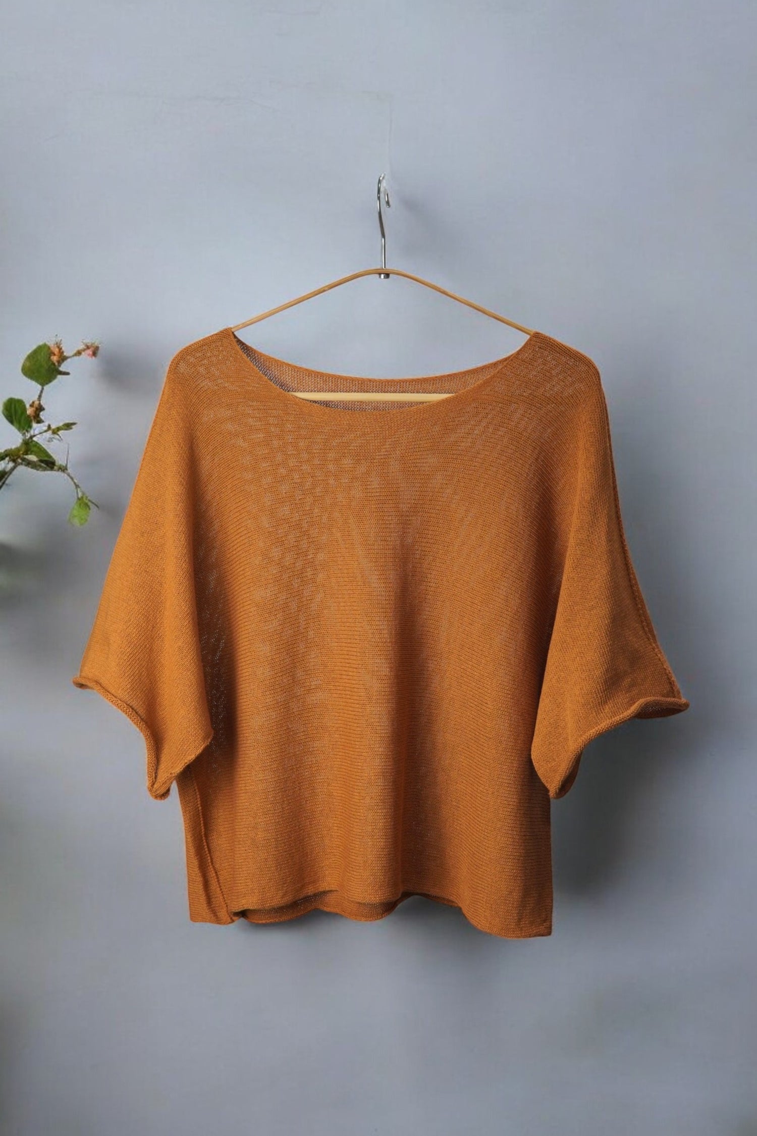Bluză din tricot subțire în nuanță ruginiu-aramie, afișată pe umeraș, fundal gri.