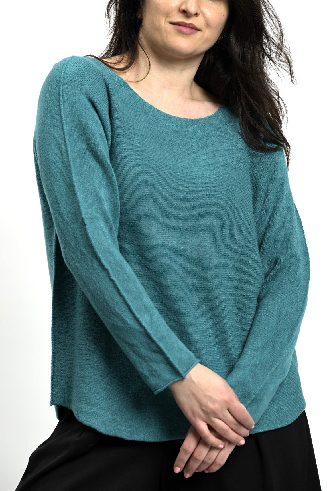 Bluză simplă din tricot verde, cu tiv rotunjit și croială lejeră, purtată cu pantaloni negri.