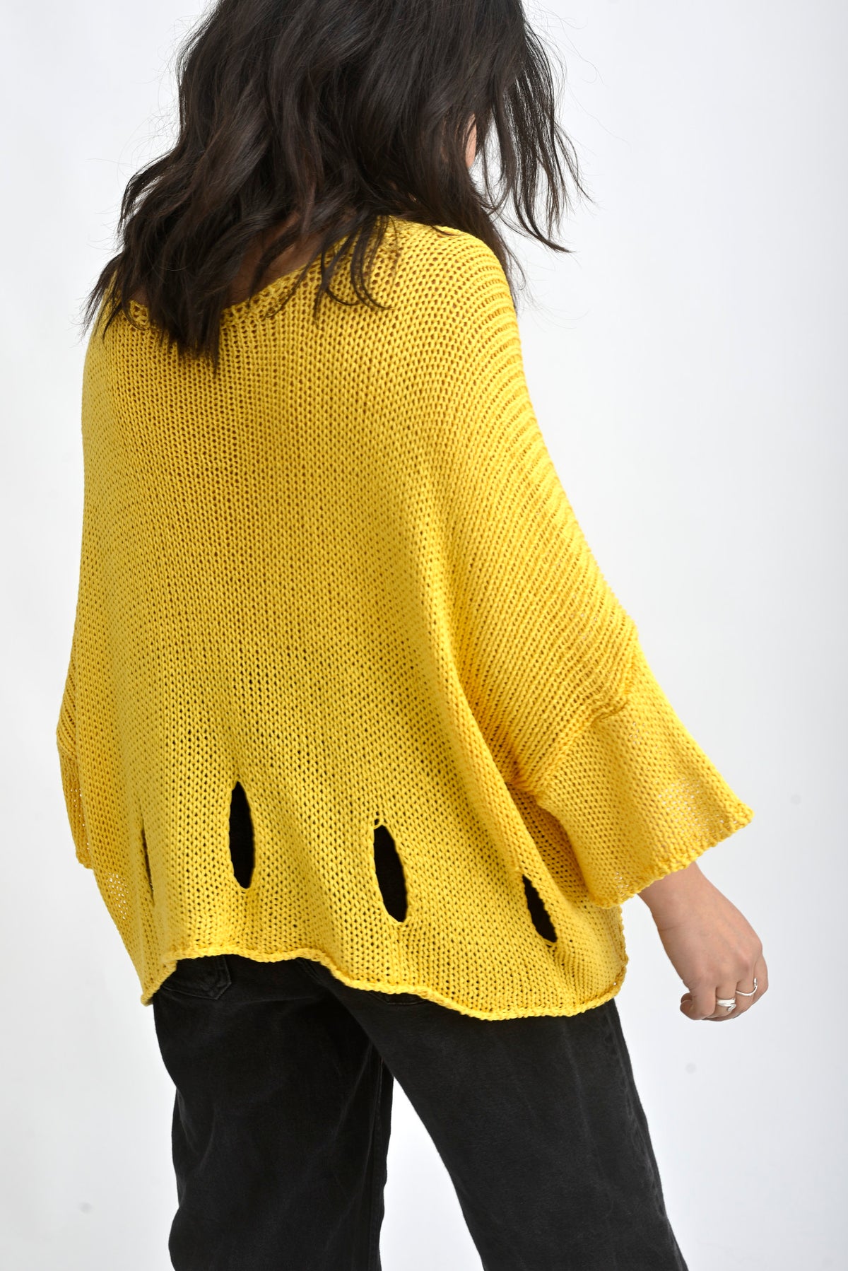 Spatele unei bluze galbene tricotate cu rupturi decorative și textură aerată, stil casual modern