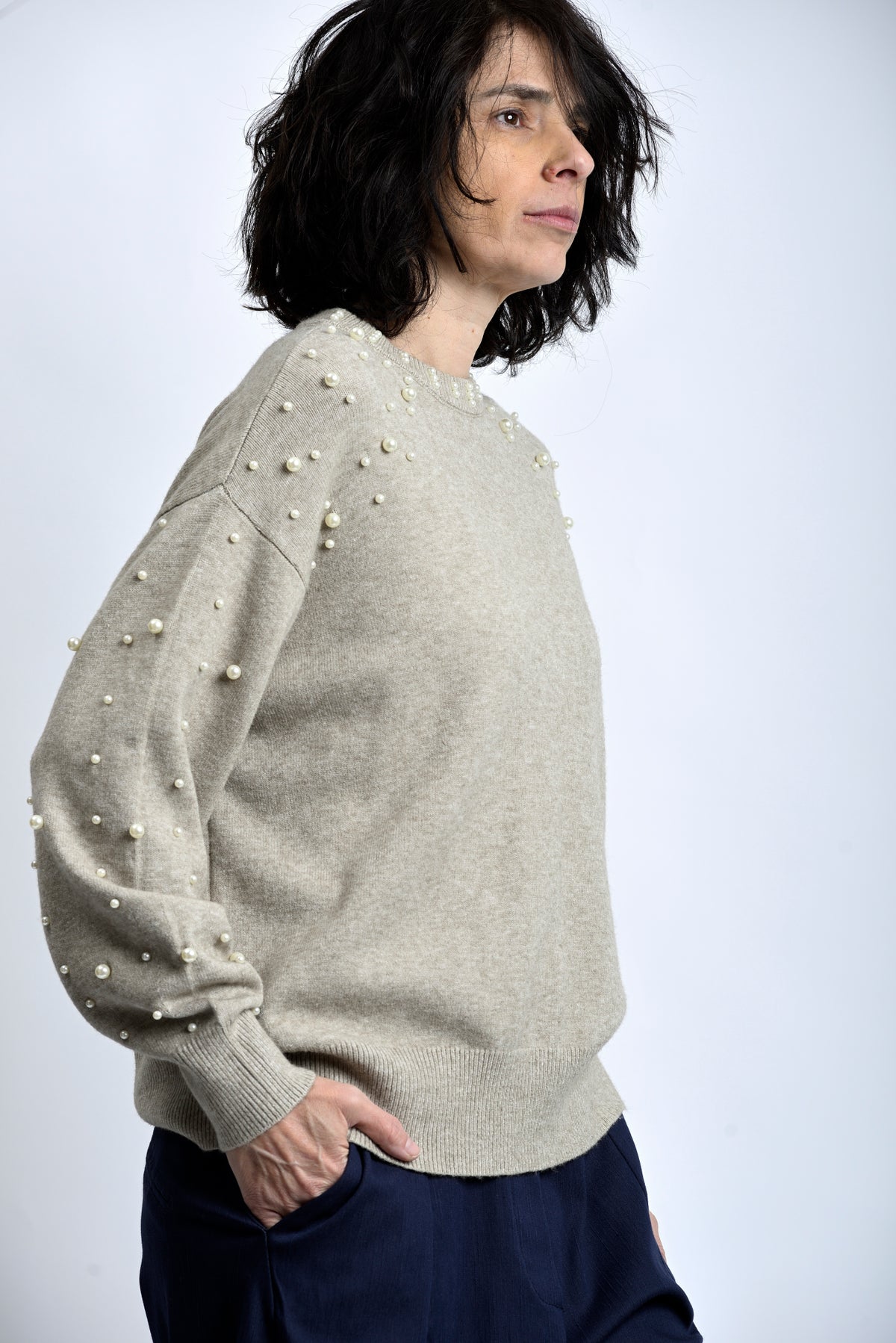 Vedere laterală bluză tricotată bej cu perle aplicate, croială lejeră și textură moale.