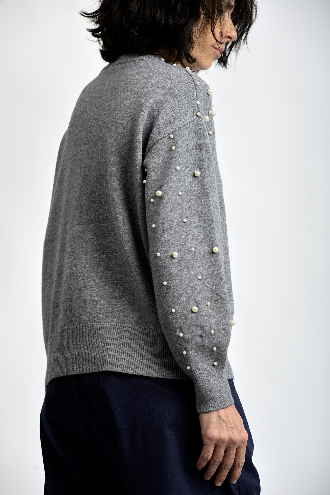 Vedere laterală bluză tricotată cu perle decorative și umeri căzuți, textură fină și manșete elastice.