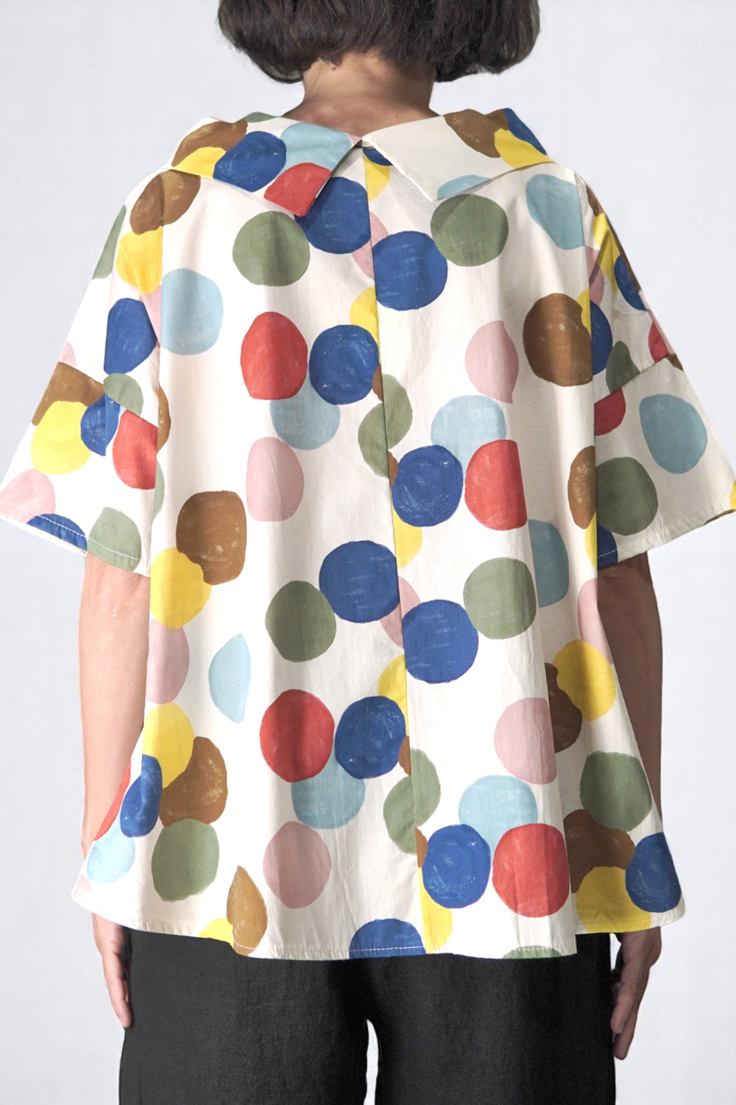 Vedere din spate a bluzei cu croială în A și guler lat, imprimeu polka dots.