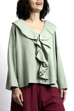 Vedere laterală bluză verde salvie cu mâneci lungi și croială oversize, umeri căzuți și cădere naturală.