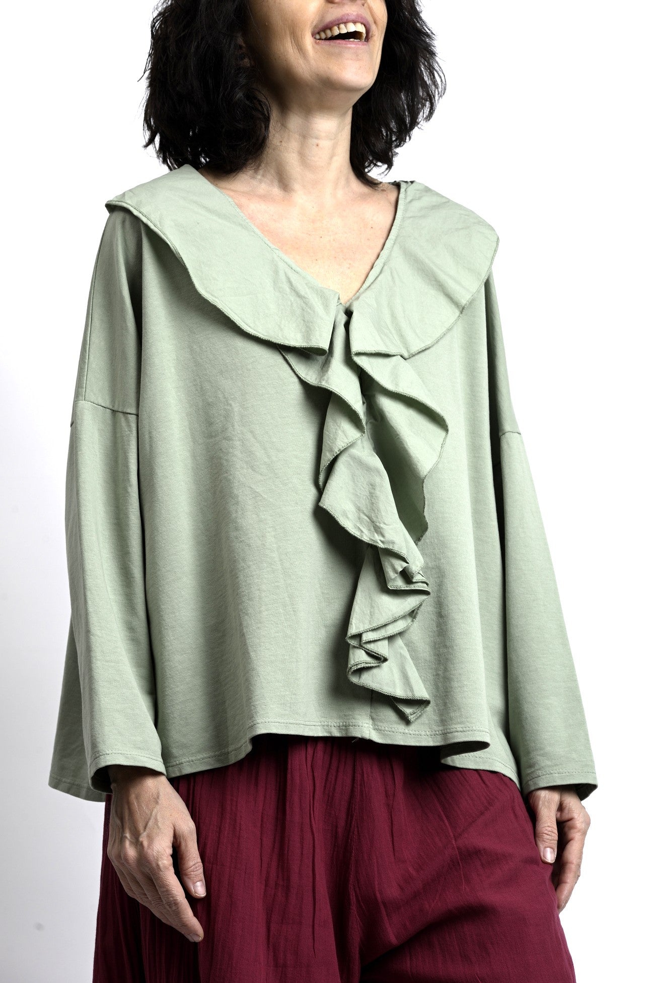 Vedere laterală bluză verde salvie cu mâneci lungi și croială oversize, umeri căzuți și cădere naturală.