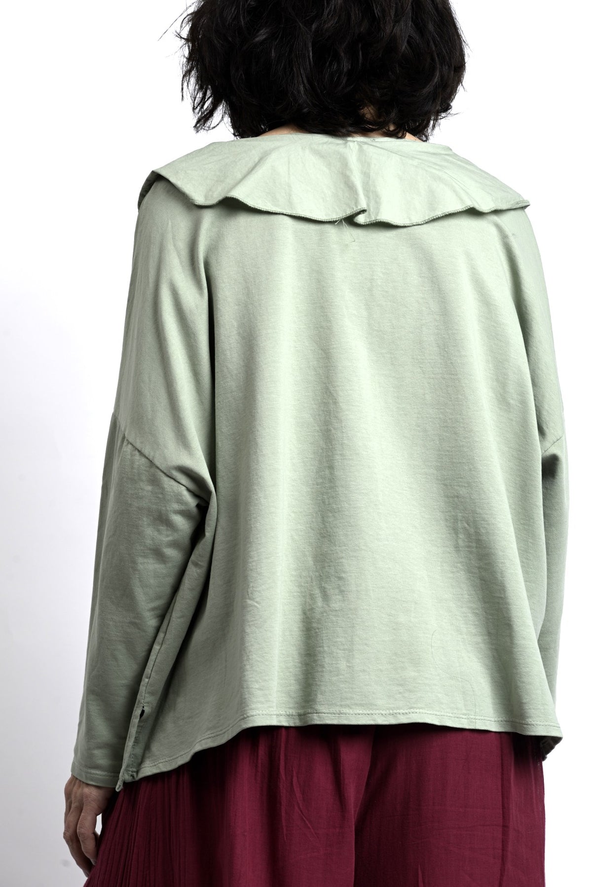 Bluză verde salvie văzută din spate, croială amplă cu umeri căzuți și tiv drept, aspect fluid și lejer.