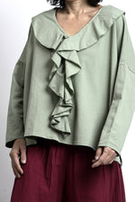 Detaliu bluză verde salvie cu decolteu în V și volane suprapuse, finisaj curat și material moale din bumbac.