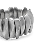 Detaliu lateral al brățării elastice din aluminiu reciclat, cu elemente sculpturale argintii dispuse compact.