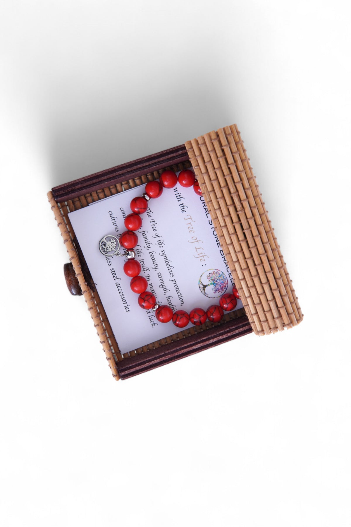 Brățără din howlit roșu fotografiată în cutia deschisă din bambus, surprinsă din unghi lateral.