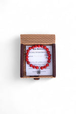 Brățară din howlit roșu, prezentată într-o cutie împletită din bambus, pe fundal alb.