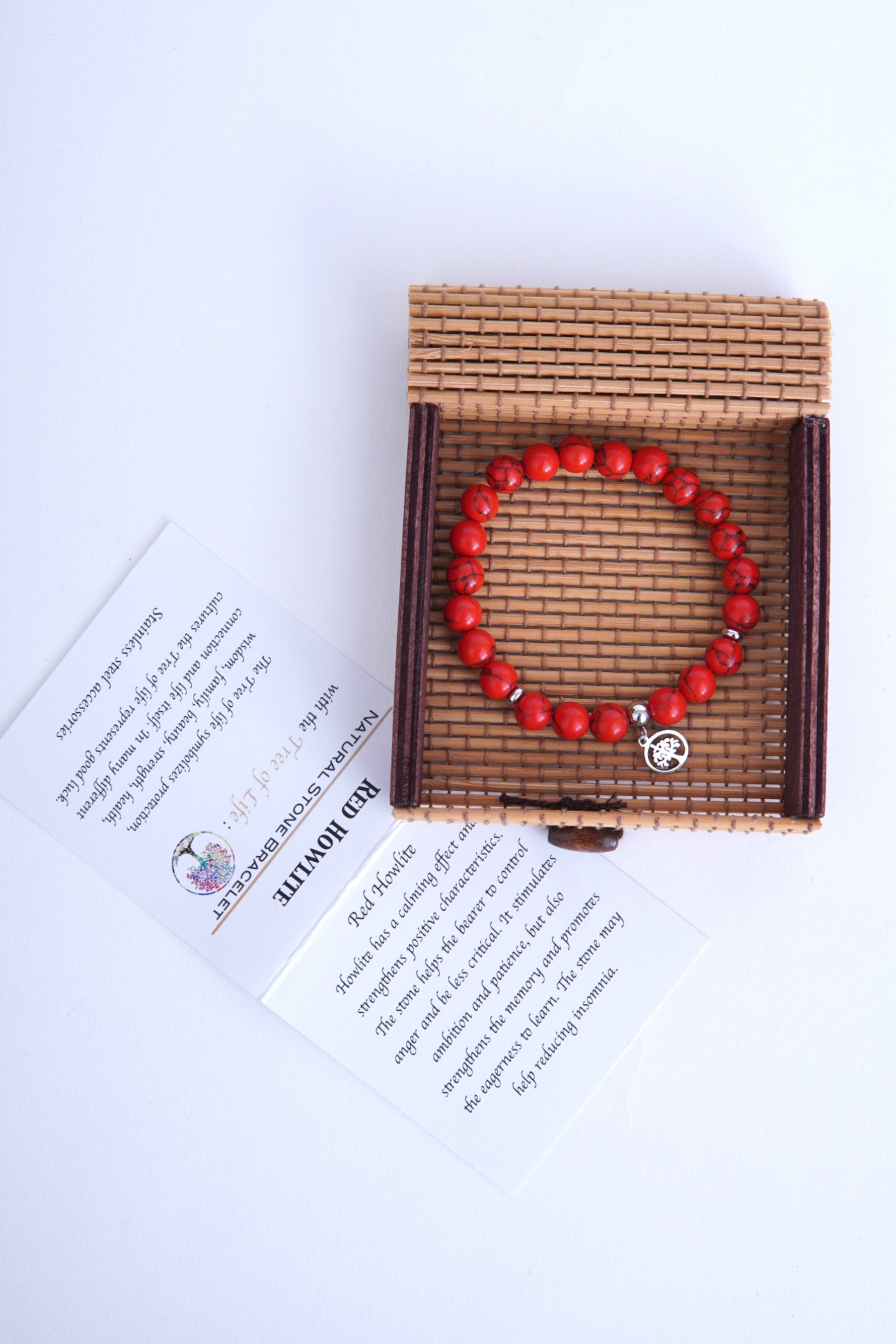 Brățară elastică din howlit roșu, așezată în cutia de bambus alături de cartonul de prezentare.