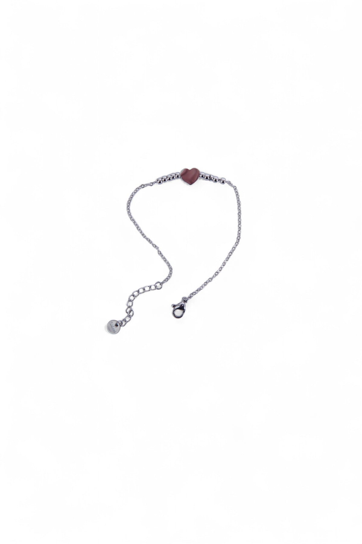 Brățară argintie din oțel inoxidabil, cu pandantiv inimă și biluțe mici, așezată delicat pe fundal alb.