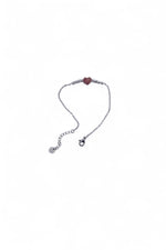 Brățară argintie din oțel inoxidabil, cu pandantiv inimă și biluțe mici, așezată delicat pe fundal alb.